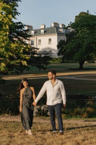a man and woman holding hands while walking in front of a house at The Langley, a Luxury Collection Hotel, Buckinghamshire in Iver