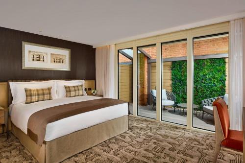 a bedroom with a large bed and sliding glass doors at The Langley, a Luxury Collection Hotel, Buckinghamshire in Iver