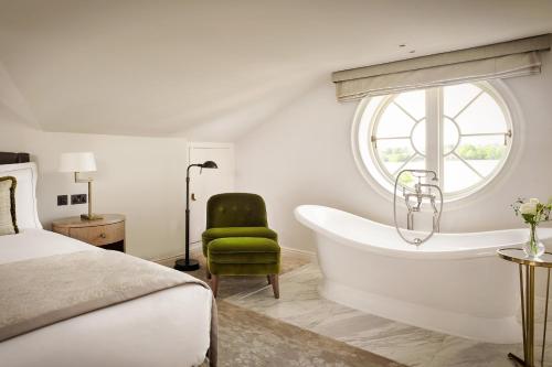 a bedroom with a bed and a tub and a window at The Langley, a Luxury Collection Hotel, Buckinghamshire in Iver
