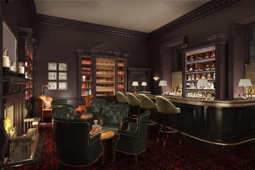 a bar with green chairs and a bar counter at The Langley, a Luxury Collection Hotel, Buckinghamshire in Iver