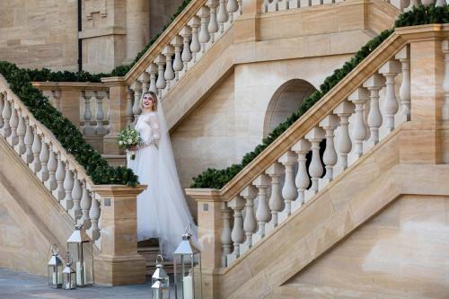 a bride walking down the stairs of a building at The Langley, a Luxury Collection Hotel, Buckinghamshire in Iver