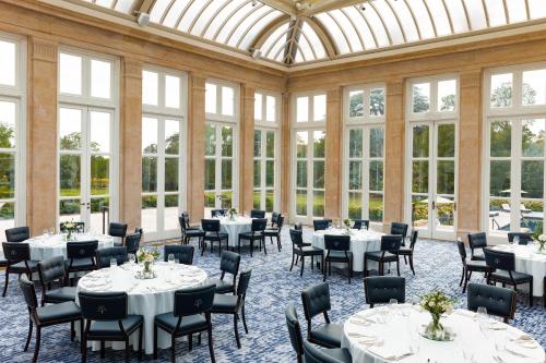 a dining room with tables and chairs and windows at The Langley, a Luxury Collection Hotel, Buckinghamshire in Iver