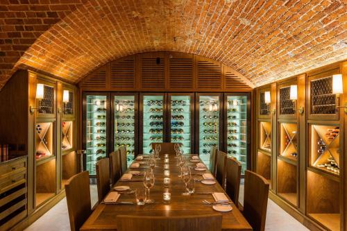 a dining room with a long table and a wine cellar at The Langley, a Luxury Collection Hotel, Buckinghamshire in Iver