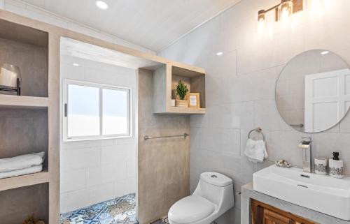 a bathroom with a toilet and a sink and a mirror at Casa amor del sol apartment # 3 in Tarcoles