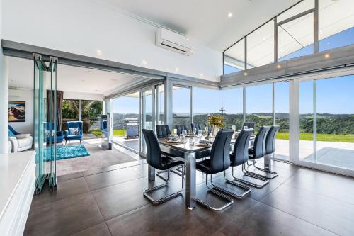a dining room with a table and black chairs at Luxury Hilltop Villa with Breathtaking Views- Perfect for Family Stays & Events in Waiwera