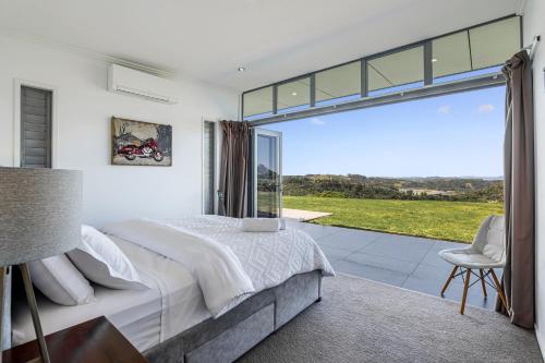 a bedroom with a bed and a large window at Luxury Hilltop Villa with Breathtaking Views- Perfect for Family Stays & Events in Waiwera