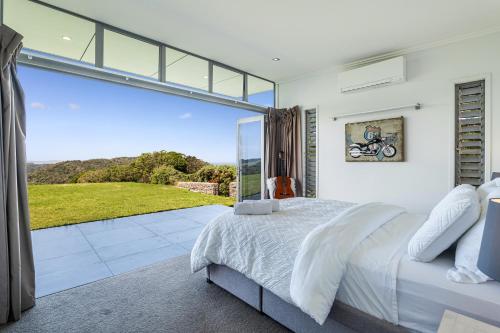 a bedroom with a bed and a large glass window at Luxury Hilltop Villa with Breathtaking Views- Perfect for Family Stays & Events in Waiwera