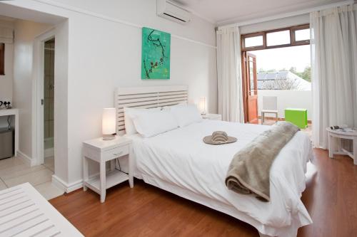 a white bedroom with a white bed and a window at The Queen Of Calitzdorp in Calitzdorp