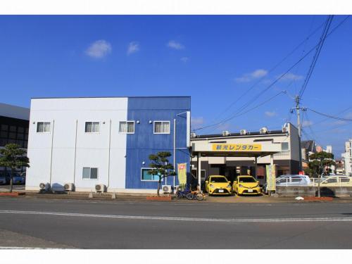 two yellow cars parked in front of a car dealership at 民宿かんこう in Goto