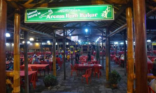 a restaurant with red tables and a green sign at DD Empire Homestay in Jeram