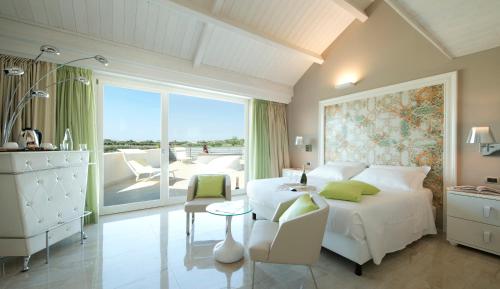ein Schlafzimmer mit einem weißen Bett, einem Tisch und einem Balkon in der Unterkunft Wellness Spa Hotel Principe Fitalia in Syrakus
