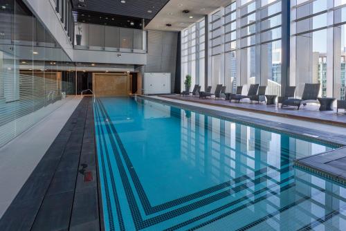 a large swimming pool with chairs in a building at Stunning Burj Khalifa & Downtown Views - Elegant 1BR in The Iconic Index Tower in Dubai