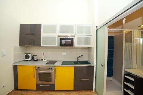 a kitchen with yellow and white cabinets and a sink at Flat On Andrássy Avenue in Budapest