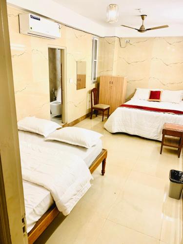 a hotel room with two beds and a bathroom at Luxorion Lodge in Bengaluru