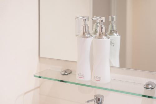 a bathroom with two white bottles on a glass shelf at Hotel ARU KSP in Kawasaki