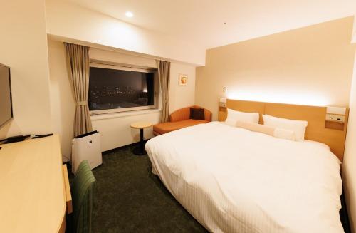 a hotel room with a white bed and a window at Hotel ARU KSP in Kawasaki