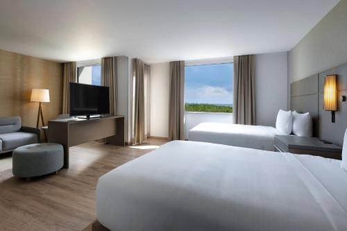 カンクンにあるResidence Inn by Marriott Cancun Hotel Zoneの大型ベッドとテレビが備わるホテルルームです。