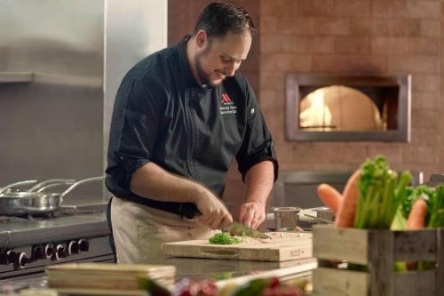 a man in a kitchen preparing food on a cutting board at Raleigh Marriott City Center in Raleigh