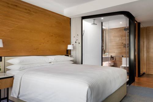a bedroom with a large white bed and a bathroom at Hong Kong Ocean Park Marriott Hotel in Hong Kong