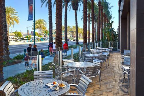 a row of tables and chairs on a sidewalk with palm trees at SpringHill Suites by Marriott at Anaheim Resort Area/Convention Center in Anaheim