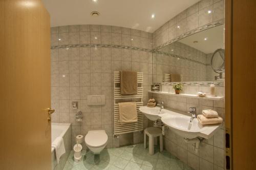 a bathroom with a sink and a tub and a toilet at Pension Alwin in Lech am Arlberg