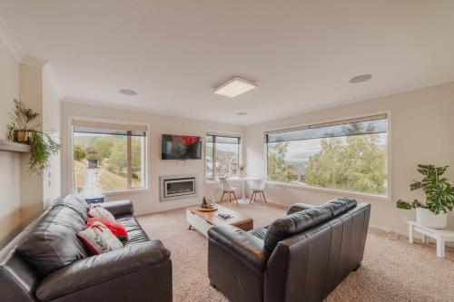 a living room with two leather couches and a tv at Starlight Lakeview Vista - 5BR Hideaway & Hot Tub in Lake Tekapo