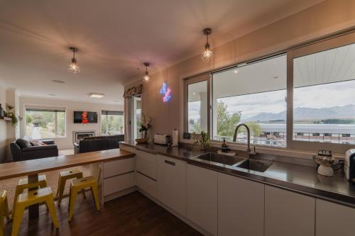 a kitchen with a sink and a large window at Starlight Lakeview Vista - 5BR Hideaway & Hot Tub in Lake Tekapo