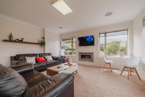 a living room with a leather couch and a table at Starlight Lakeview Vista - 5BR Hideaway & Hot Tub in Lake Tekapo