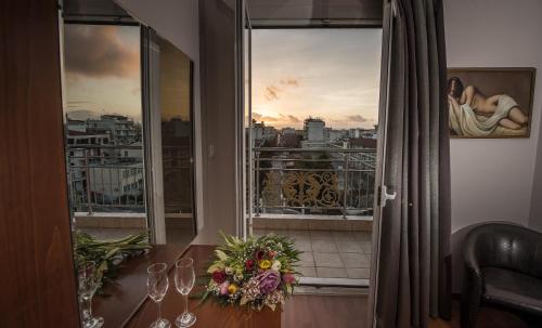 a table with wine glasses and flowers on a balcony at Hotel Olympos in Pýrgos