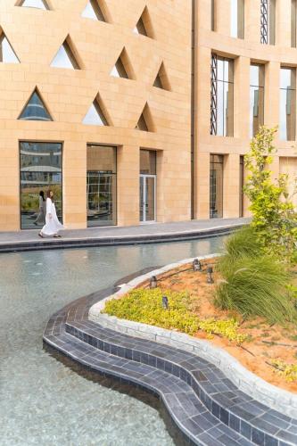 a bride and groom walking in front of a building at JW Marriott Hotel Riyadh in Riyadh