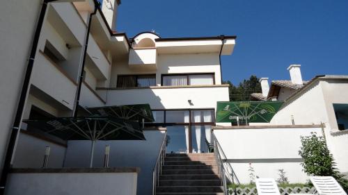 a white building with stairs leading up to it at Hotel Aleksievata Kashta in Gurgulyat
