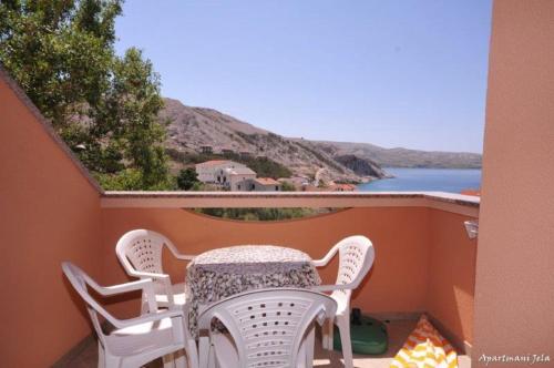 a table and chairs on a balcony with a view of the ocean at Apartments Jela in Metajna