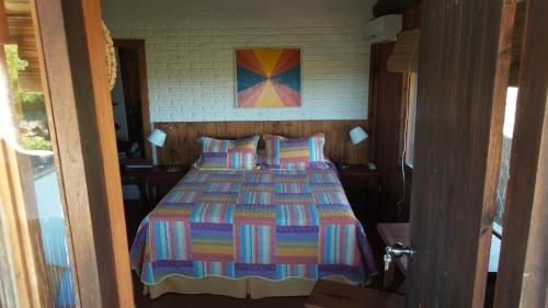 a bedroom with a bed with a colorful quilt at Hotel El Refugio nudista naturista opcional in Chihuahua