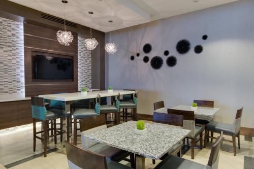 a dining room with tables and chairs and a tv at Residence Inn by Marriott Daytona Beach Oceanfront in Daytona Beach