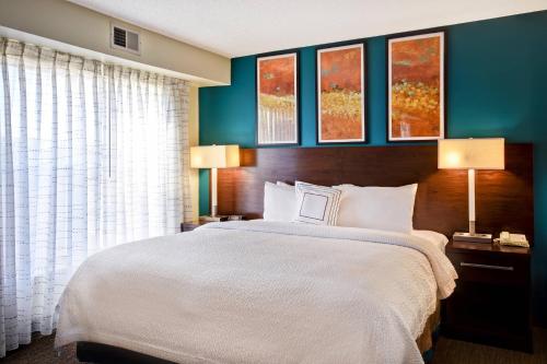 a bedroom with a large bed with two lamps and three paintings at Residence Inn by Marriott Dayton Beavercreek in Beavercreek
