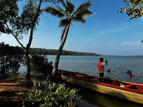 a man standing in a boat next to a palm tree at Lake Homes in Varkala