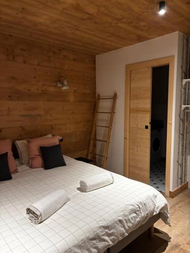 - une chambre avec un grand lit blanc et des murs en bois dans l'établissement Appartement GRABILLES, à Praz-sur-Arly