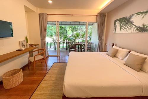 a bedroom with a large bed and a balcony at Nisasiri Boutique Resort in Laem Sing