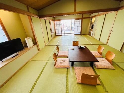 a room with a table and chairs and a tv at Hotel Takasago in Kochi