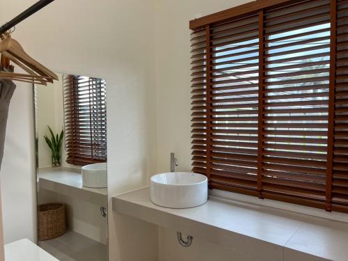 a bathroom with two sinks and a large window at Nisasiri Boutique Resort in Laem Sing