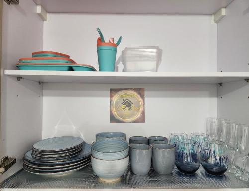 a shelf filled with plates and bowls and glasses at Simpson's Little Gem in Kingston