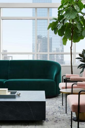 a green couch in a living room with a plant at The Luxury Collection Hotel Manhattan Midtown in New York