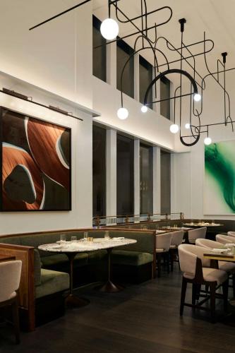 a restaurant with tables and chairs and a chandelier at The Luxury Collection Hotel Manhattan Midtown in New York