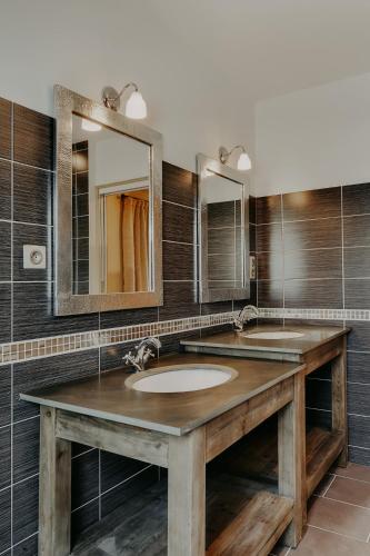 une salle de bain avec deux lavabos et deux miroirs dans l'établissement Maison Saunières, à Saunières