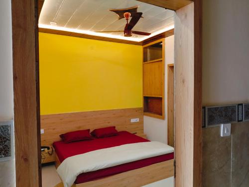 Cama pequeña en habitación con pared amarilla en Shri Rajadhiraj Ashray- Nr Mathura Railway Station, en Mathura