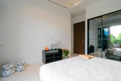 a white bedroom with a large bed and a mirror at Seaview Villa Near Naithon Beach Phuket in Nai Thon Beach