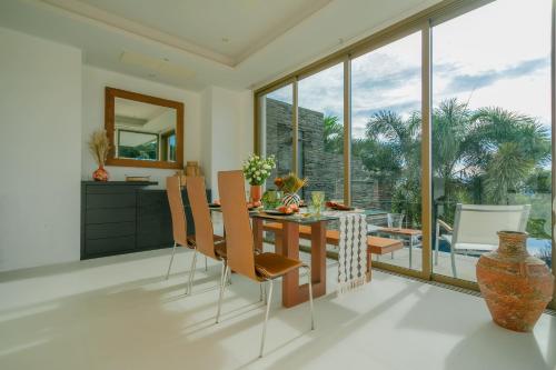 a dining room with a table and chairs and a large window at Seaview Villa Near Naithon Beach Phuket in Nai Thon Beach