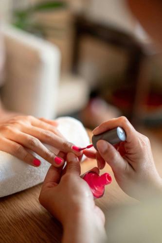 a woman with red nail polish is cutting a persons nails at Phuket Marriott Resort & Spa, Merlin Beach in Patong Beach