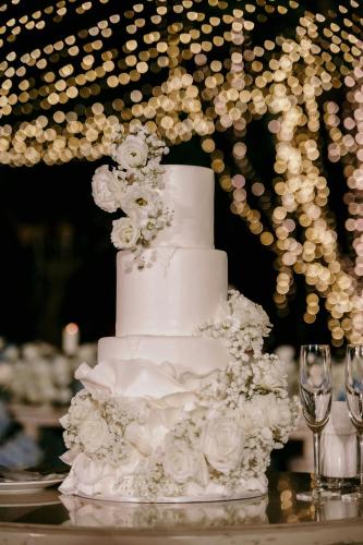 a white wedding cake on a table with wine glasses at Phuket Marriott Resort & Spa, Merlin Beach in Patong Beach
