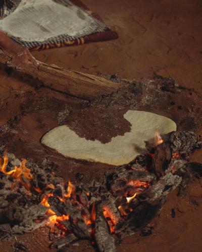 a piece of bread is cooking over a fire at Bivouac Joudour Sahara in Mhamid